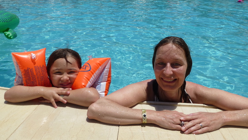 Barn med simdynor badar i poolen