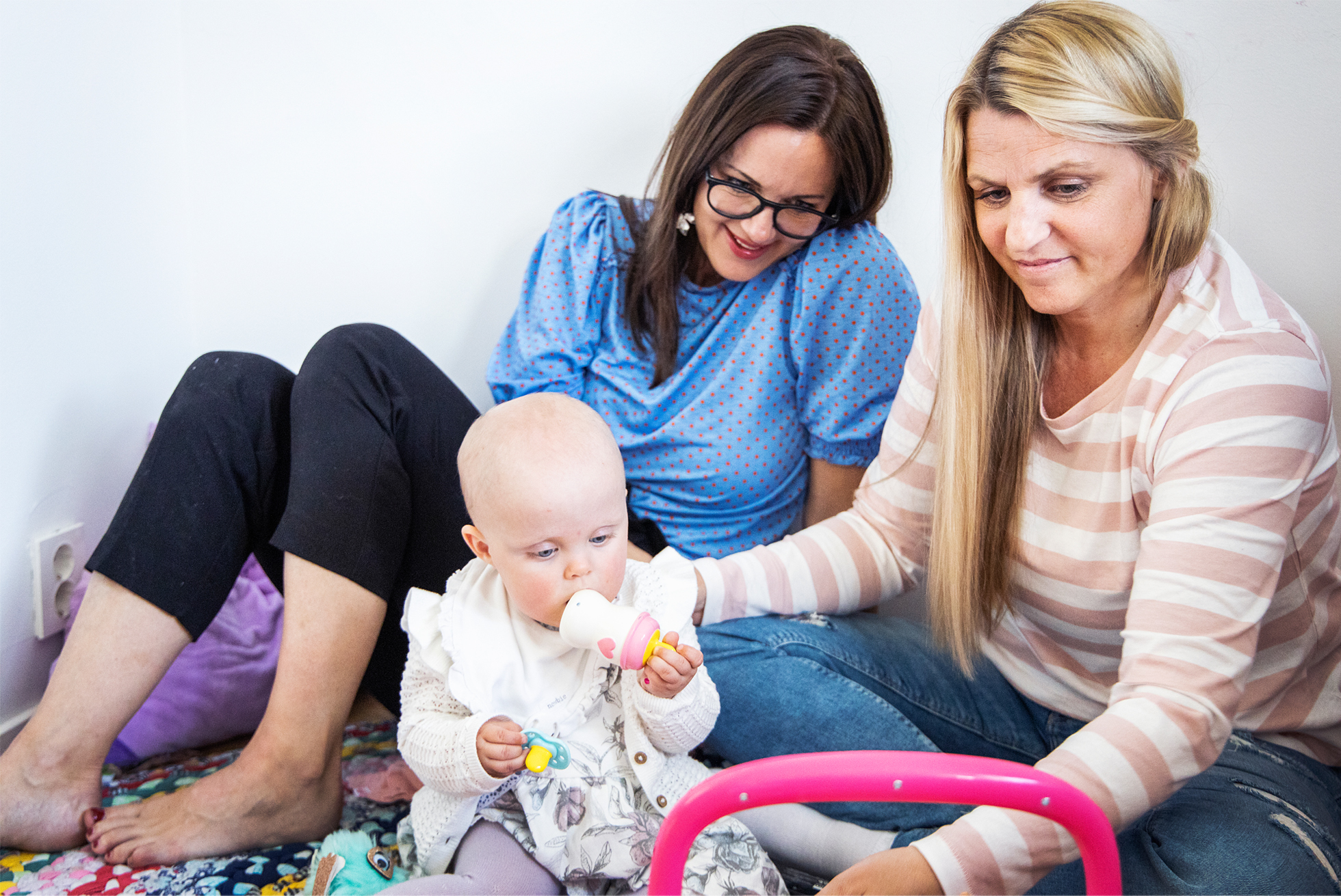 Josephine och Hannah leker med Ebba på golvet