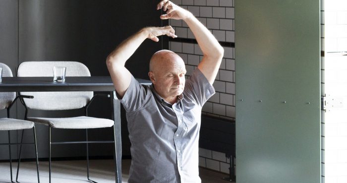 Skallig man i yogaposition med bord bakom